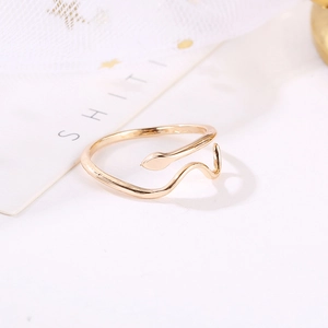Minimalist gold snake-shaped open ring with elegant curved lines on a white desk
