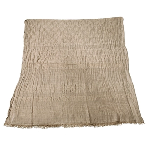 Detail of light brown men's scarf showing jacquard weave, fringe trim and wrinkled texture