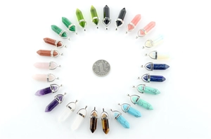 Macro view of assorted hexagonal crystal quartz pendants surrounding a coin for size reference