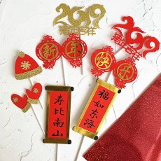 Flat lay of red and gold glitter New Year cake toppers with traditional Chinese characters