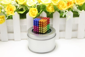 Macro shot of colorful magnetic balls stacked on a round silver storage tin lid