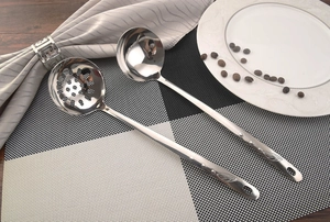 Polished stainless steel soup ladle and slotted spoon set on a checkered placemat