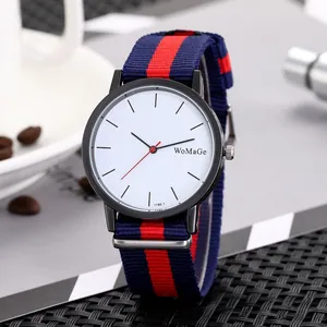 Detail view of quartz watch with black case and red-blue NATO strap on a textured surface