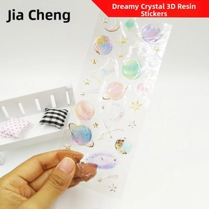 Macro shot of 3D galaxy resin stickers with gold foil details and glitter space designs