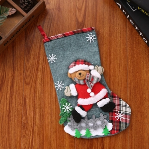 Detailed view of gray linen Christmas stocking with red plaid trim and 3D bear applique