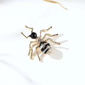 Détail de broche insecte dorée avec tête en émail noir et cristaux sur fond blanc