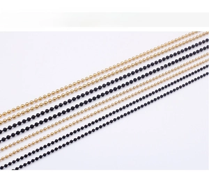 Detailed view of parallel golden and black stainless steel ball chains on white background