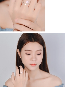 Detail of silver open ring with pink cherry blossom and leaves worn by a model