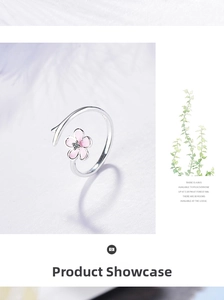 Detail of pink cherry blossom ring with branch band and zircon center on feathers