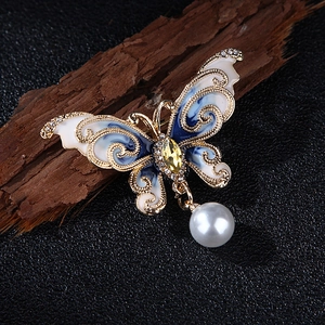 Détail macro d'une broche papillon en émail avec pierre jaune et pendentif en perle