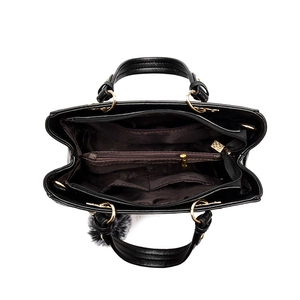 Minimalist black handbag with dual main compartments and a plush grey charm accent