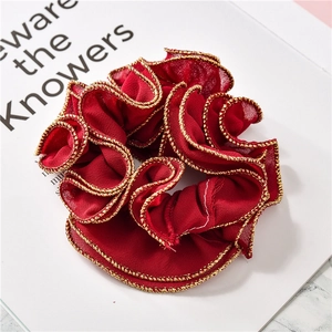 Detail of red scrunchie with gold metallic trim on a minimalist magazine background