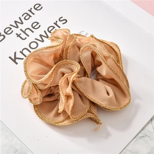 Close-up of champagne scrunchie with gold ruffled edges and soft pleated fabric