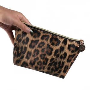 Detail view of the leopard print cosmetic bag with a gold zipper and trapezoid shape