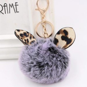 Close-up of purple plush ball keychain with leopard print ears and gold lobster clasp