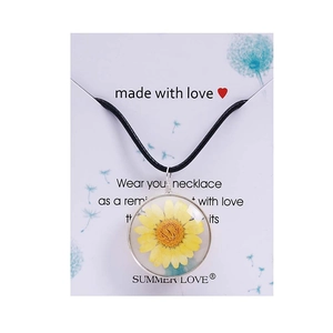 Detail of handmade glass pendant necklace with real yellow daisy flower and black wax cord
