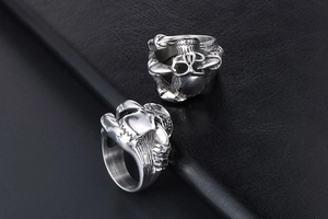 Macro shot of silver gothic punk rings with eagle claw design on black leather background