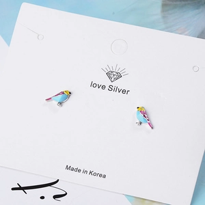 Minimalist enamel bird stud earrings in blue and yellow on white jewelry card