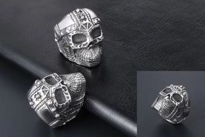 Detailed close-up of a punk-style stainless steel skull ring with intricate gothic carvings
