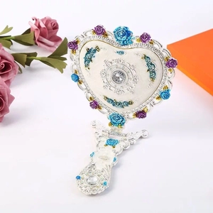 Detailansicht herzförmiger Handspiegel mit silbernem Relief und bunten Rosen-Verzierungen