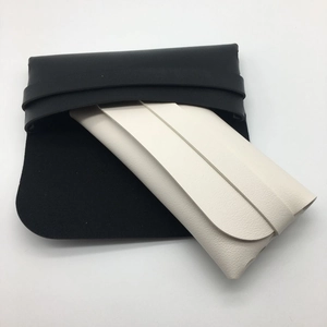Detail of minimalist leather cases in black and cream white with flap and strap closure
