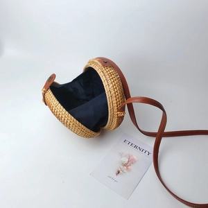 Handmade round rattan crossbody bag with brown leather strap and navy blue fabric lining