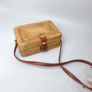Detail of hand-woven rattan square bag with brown leather strap and buckle closure