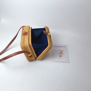 Detail of handwoven rattan bag with dark blue lining and brown leather strap buckle