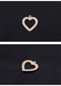 Detail of a golden heart pendant with inset rhinestones on black leather surface