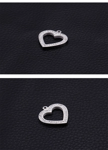 Macro shot of silver hollow heart pendant with sparkling crystals on black leather base