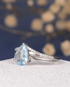 Macro shot of a teardrop-shaped light blue gemstone ring with small diamonds on the side
