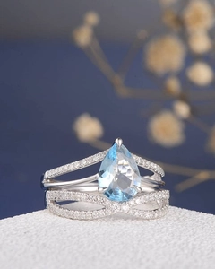 Macro shot of a pear-cut blue sapphire ring set with a V-shaped pavé diamond wedding band