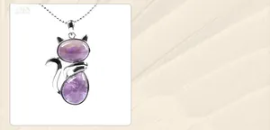 Detail of a cat-shaped pendant necklace featuring purple agate stones and a silver bead chain