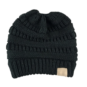 Detail view of black chunky knit ponytail beanie with textured weave and faux leather label