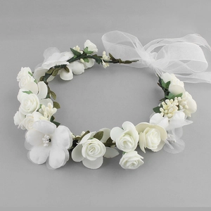 Detailed view of white fabric floral wreath with satin ribbons and artificial berries
