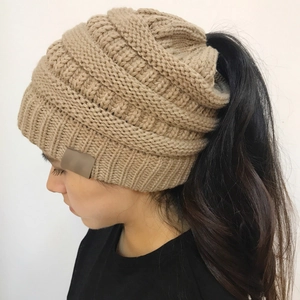 Detail of khaki cable knit beanie with side leather patch and ponytail opening