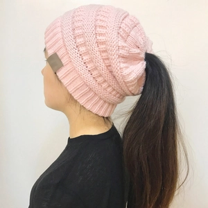 Detail of pink knitted ponytail beanie showing thick texture and functional top opening