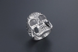 Macro detail of gothic skull ring featuring intricate floral carvings and silver finish