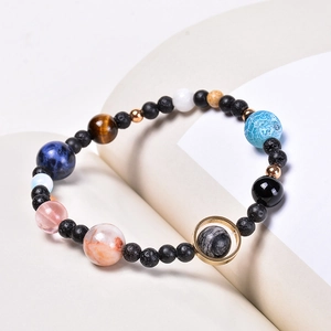 Detail of solar system bracelet with natural stones on a book page background