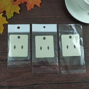 Macro detail of three jewellery display cards and transparent poly bags on wood surface