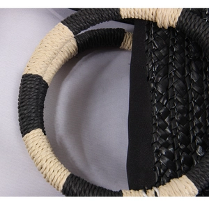 Close-up of black and beige woven straw bag with circular rope handles and texture
