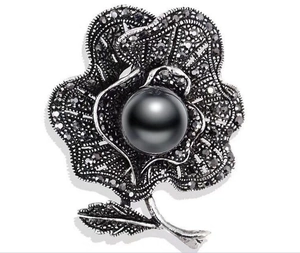 Macro detail of retro gun-black rose brooch with dark pearls and sparkling rhinestones