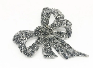 Detail of vintage gun black bow brooch featuring rhinestones and dark mosaic texture