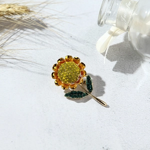 Detail of sunflower brooch with golden petals and yellow rhinestones on a rustic background
