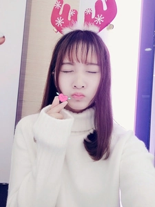 Young woman in a white sweater wearing a red reindeer antler headband with white snowflakes