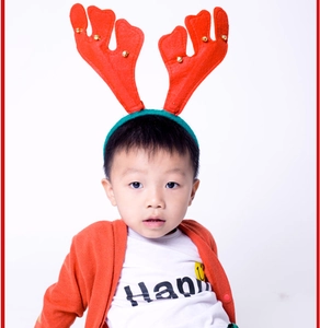 Detail of child wearing red reindeer antler headband with festive golden bells