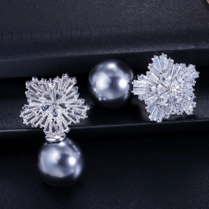 Close-up of snowflake zircon earrings with a large grey pearl drop in studio lighting