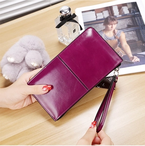 Detailed view of a purple wax leather long wallet with wrist strap on a wooden desk