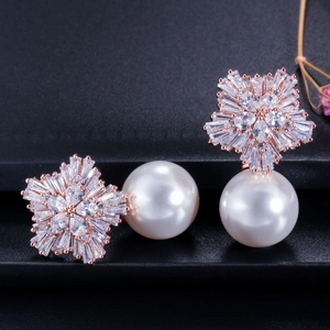Detailed shot of rose gold snowflake earrings with zircon micro-pave and large white pearls