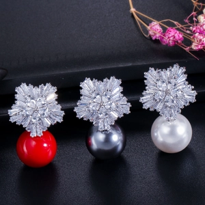 Detailed view of floral zircon earrings with red, grey, and white pearl drops on dark surface
